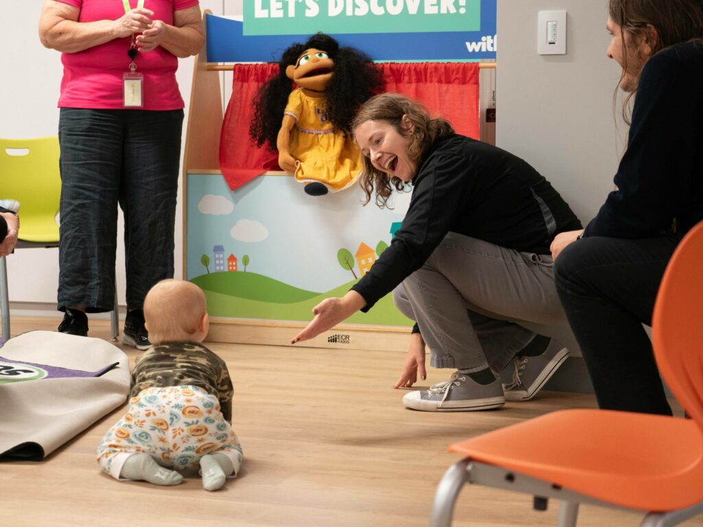 A baby crawls toward a puppet